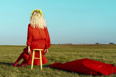 Woman with red umbrella on field against sky