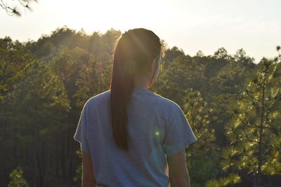 Rear view of woman standing against trees