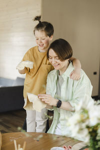 Smiling mother and son holding pizza doughs at home