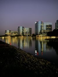 River by illuminated city against clear sky at night