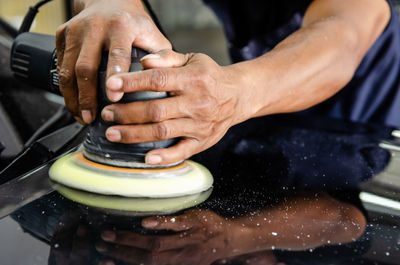 Cropped hands of manual worker cleaning car