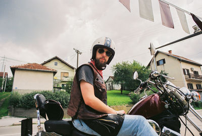 Man sitting in house against sky