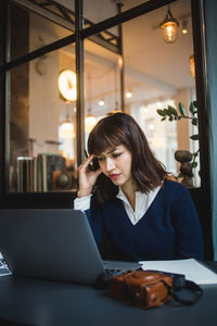 Young woman using phone while sitting on table