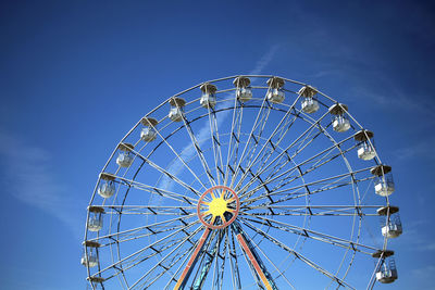 Low angle view of ferris wheel against blue sky