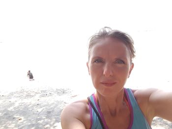 Portrait of young woman standing on beach against clear sky