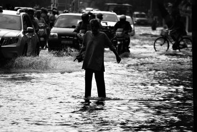 People and vehicles on road in city during flood