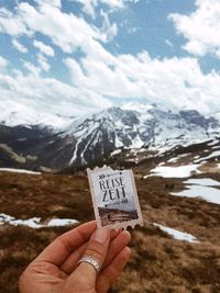 Midsection of person holding snowcapped mountain against sky