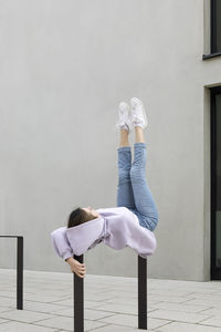 Girl with legs up lying on metal by wall