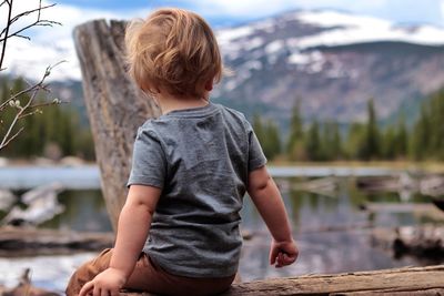 Rear view of boy on lake against mountain