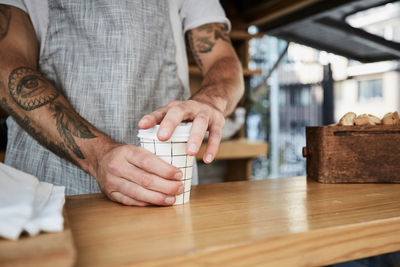 Midsection of salesman packing disposable coffee cup in food truck
