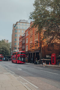 Road by buildings in city against sky