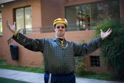 Portrait of mid adult man standing with arms outstretched against building