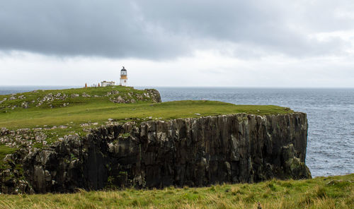 Lighthouse by sea against sky