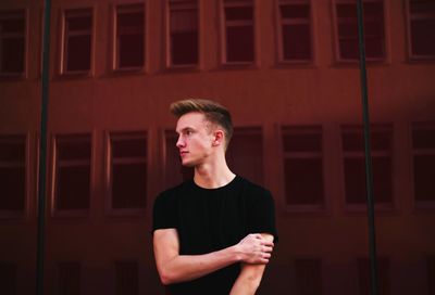 Young man standing against building