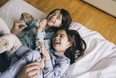 Twin girls laughing while lying on bed at home