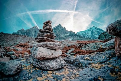 Stack of stones on rock against sky