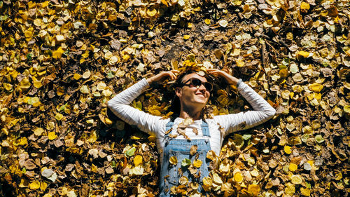 High angle view of smiling woman lying on autumn leaves
