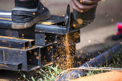 Close-up of worker using angle grinder to cut steel.