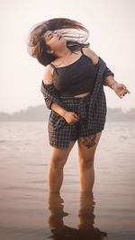 Full length of woman looking away while standing on the beach.