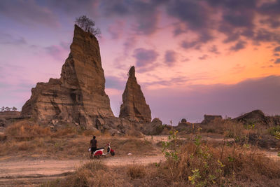 Man standing on rock formation against sky