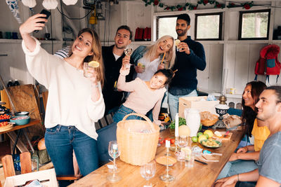 Young woman taking selfie with friends during lunch party
