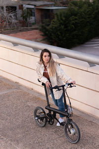 Top view of young woman leaning and holding an electric bicycle with alternative energy efficient