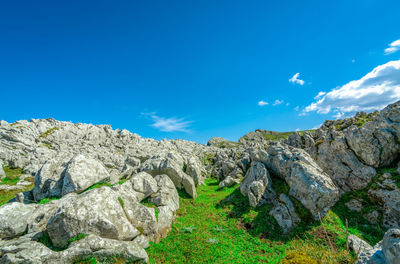 Landscape of green grass and rock hill in spring with beautiful blue sky and white clouds.