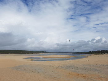 Scenic view of sandy beach against cloudy sky