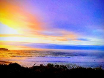 Scenic view of sea against dramatic sky during sunset