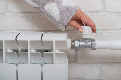 Close-up of hand holding white tap in bathroom