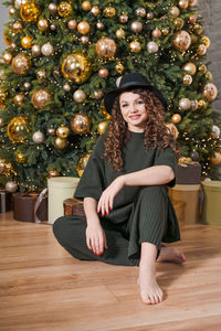 Young beautiful woman sits on floor near christmas tree and presents new year's