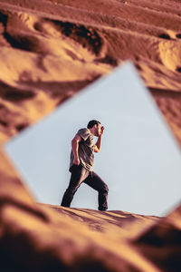 Reflection of man walking on sand in mirror