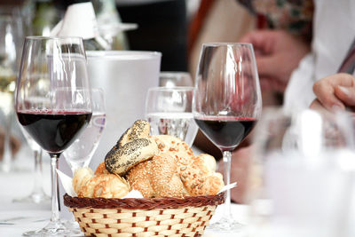 Close-up of bread in basket by wineglasses on table