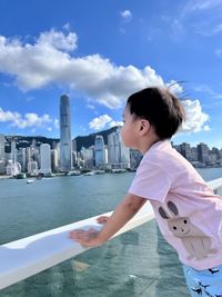 Side view of asian boy standing by sea against sky