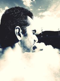 Close-up portrait of young man looking away against sky