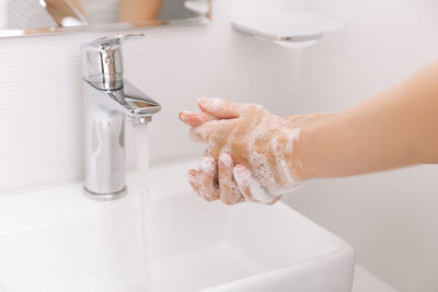 Cropped hand washing hands in sink