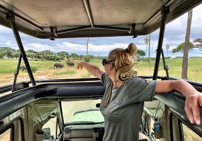 Woman pointing at elephants in safari vehicle at national park