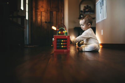 Baby girl playing with abacus while sitting on floor at home