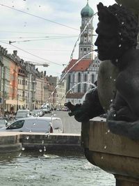 Statue by buildings in city against sky