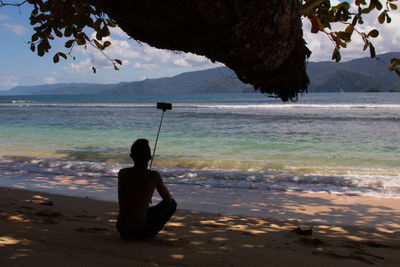 Rear view of man sitting on beach