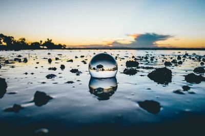 Reflection of ice on sea against sky during sunset