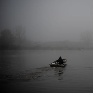 Man in boat on lake against sky