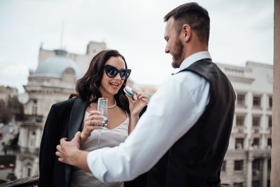 Side view of young couple standing against buildings in city