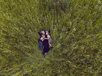 Mother in an evening dress with two daughters is lying on a green field with grass in the summer