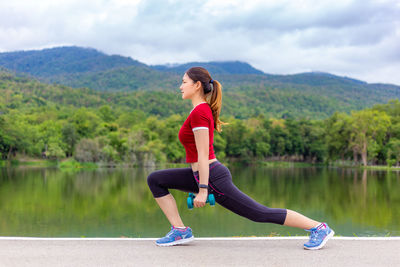 Full length of woman with arms raised in lake