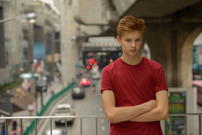 Young man standing against road in city