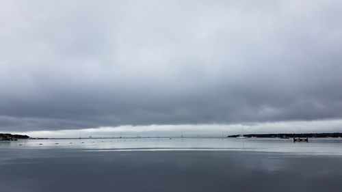 View of calm beach against cloudy sky