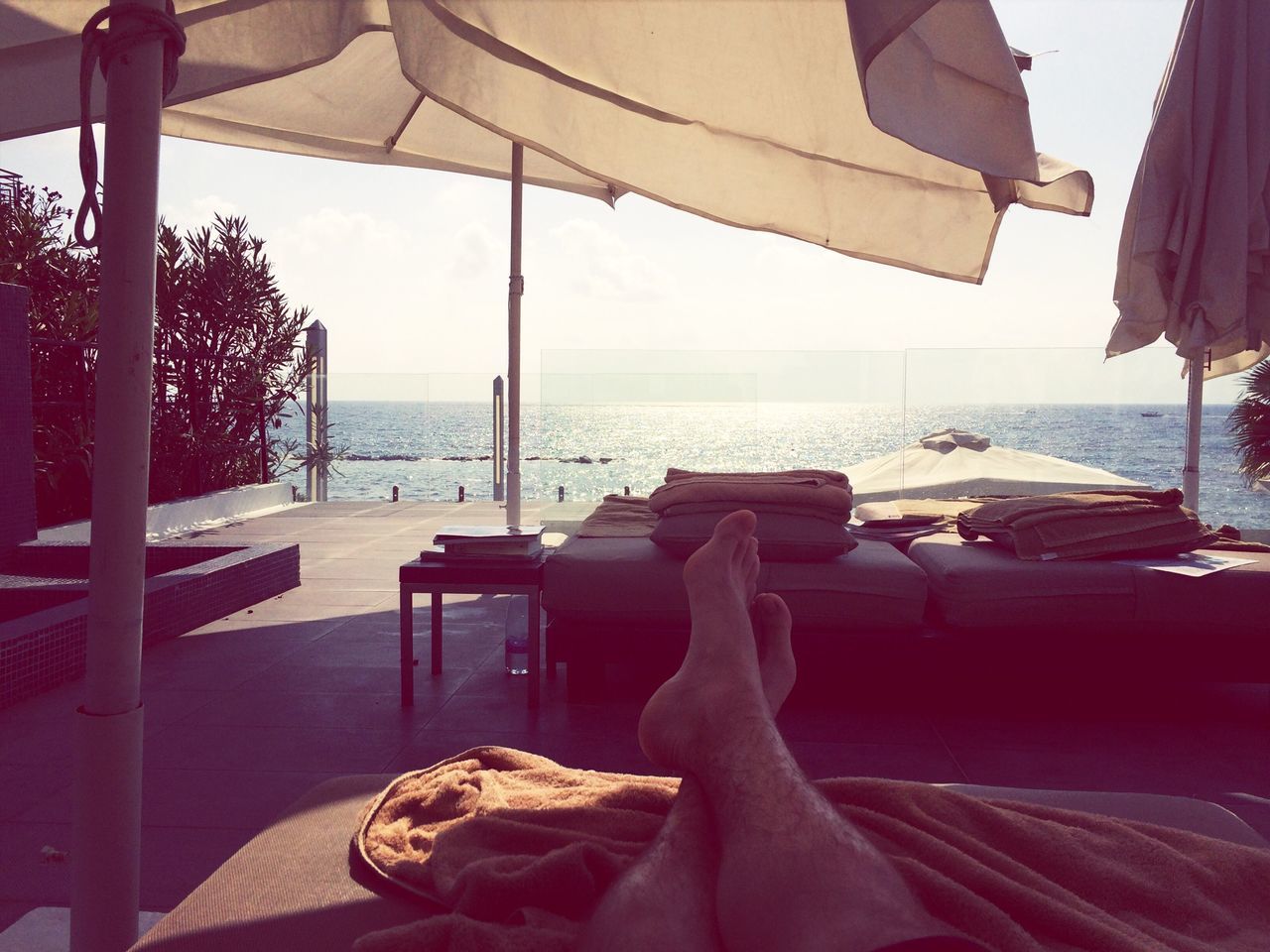 sea, horizon over water, relaxation, water, beach, chair, low section, sunlight, table, sky, person, lounge chair, vacations, parasol, indoors, sitting