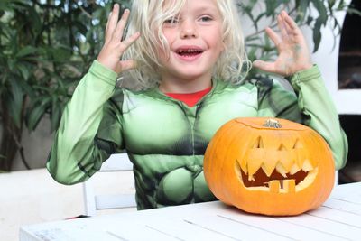 Boy in costume with jack o lantern on table