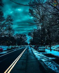 Road amidst bare trees against sky in city